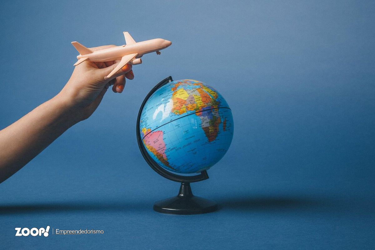 Ilustração mostrando uma pessoa segurando avião de brinquedo pasando sobre globo terrestre ilustra nosso artigo sobre: SEO e a jornada de compra dos internautas.