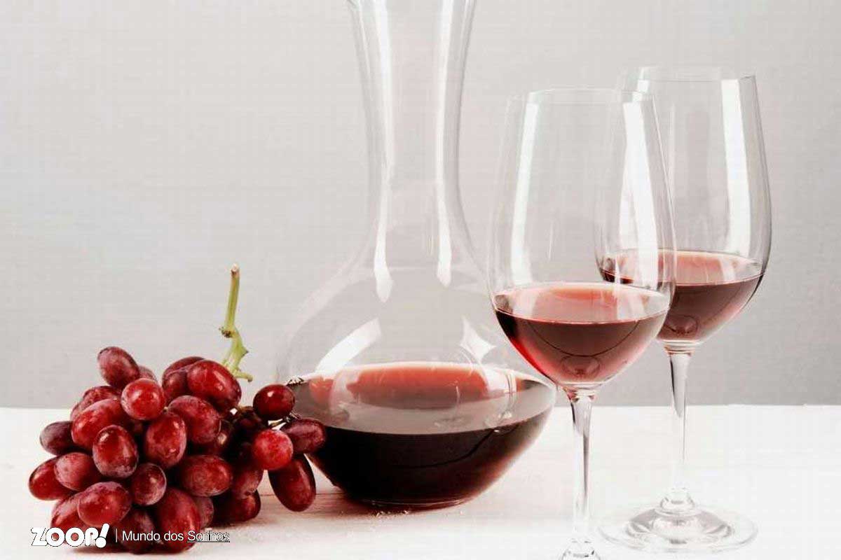 Duas taças de vinho tinto ao lado de uma garrafa ilustra nossa artigo sobre: . Sonhar com taça.